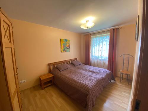a bedroom with a bed and a window and a chair at Butas Senamiestyje in Druskininkai