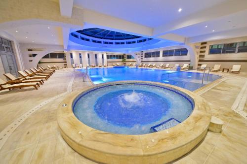 a large swimming pool in a large building with chairs at Mediteran Hotel & Resort in Budva