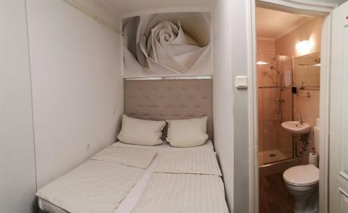 a small bed in a small room with a bathroom at Lika Panzió Gyula in Gyula