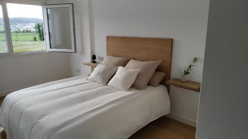 1 dormitorio con 1 cama blanca grande y ventana en Apartamento Loft Costa da Morte Vimianzo, en Vimianzo