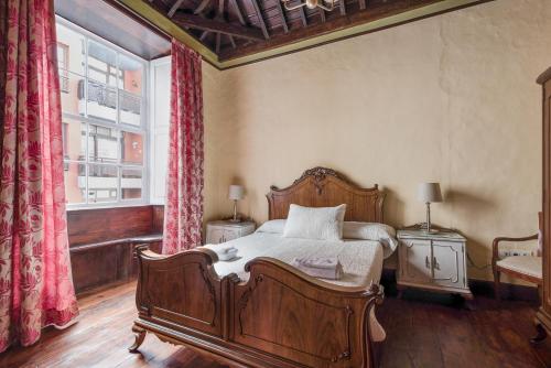 1 dormitorio con cama de madera y ventana en La Vicaría en La Laguna
