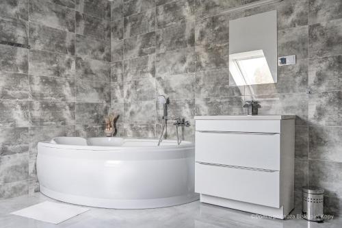 a bathroom with a tub and a sink and a mirror at Dom u podnóża Biskupiej Kopy in Jarnołtówek