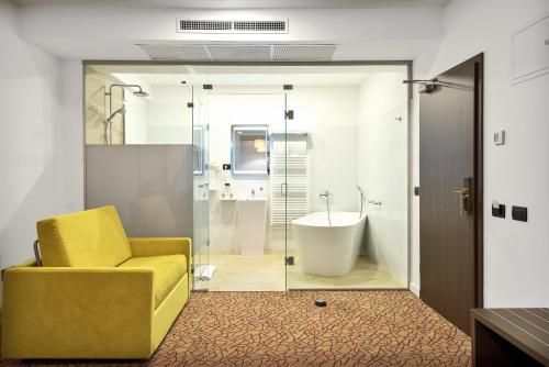 łazienka z żółtym krzesłem i wanną w obiekcie Charm Boutique Hotel w mieście Satu Mare