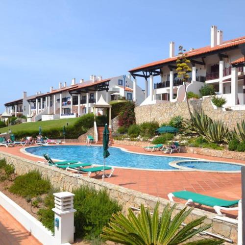 a swimming pool with chairs and umbrellas in a resort at Casa S & S in São Martinho do Porto