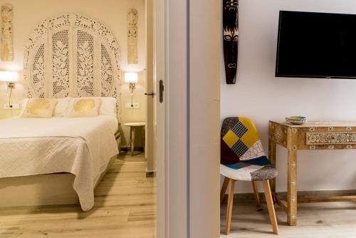 een slaapkamer met een bed, een tafel en een stoel bij Suite Capitán 1 in Cádiz