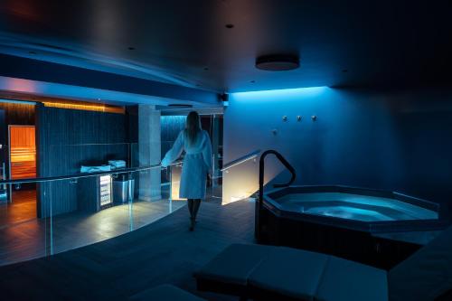 Hotel South Coast في سيلفوس: امرأة تمشي في الحمام مع حوض استحمام