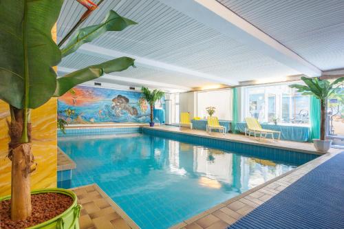 a pool with a palm tree in a hotel room at Apart Hotel Stadtgarten in Überlingen