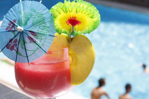 a drink with a slice of fruit and a beach umbrella at Hotel Perla in Benidorm