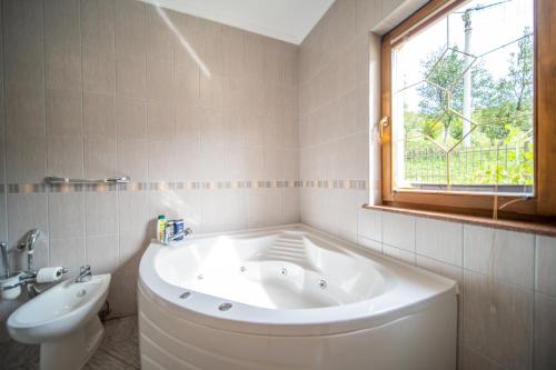 Un baño con bañera, lavabo y ventana. en The View Apartment, en Visoko