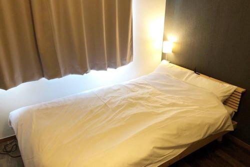 a white bed with a light on top of it at Chill Inn Honan in Tokyo
