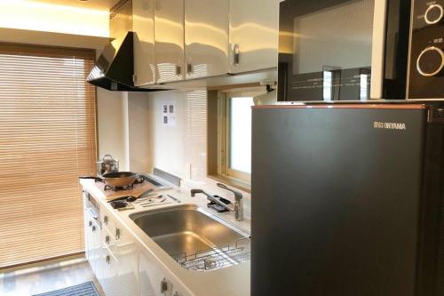 a kitchen with a sink and a refrigerator at Chill Inn Honan in Tokyo