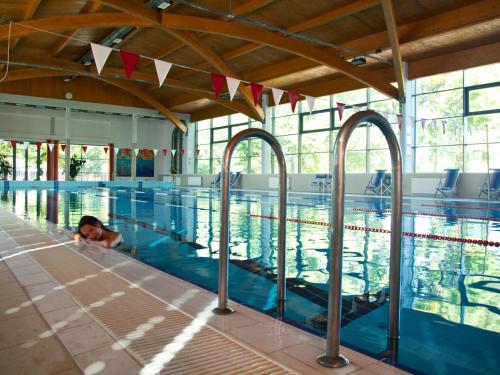 una donna che nuota in una piscina in un edificio di Pálma Apartmanok Szálláshely Százhalombatta 5a a Százhalombatta