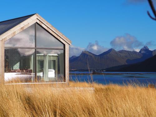 uma casa com uma janela num campo de relva alta em Steigen Lodge Sjøhytter em Engeløya