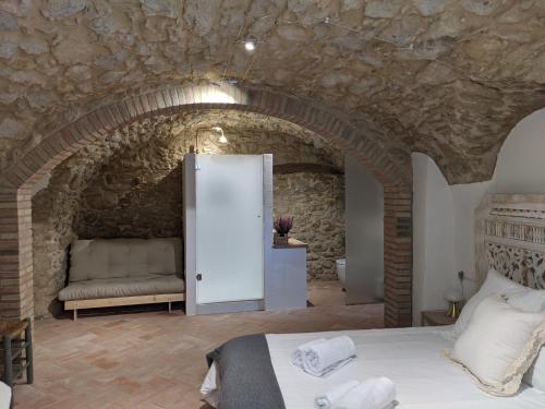 ein Schlafzimmer mit einem Torbogen mit einem Bett und einem Sofa in der Unterkunft Can Puig CAVE in La Pera