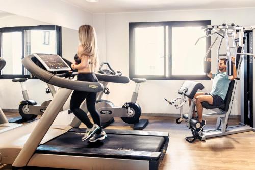 a man and a woman on a treadmill in a gym at Novotel Parma Centro in Parma