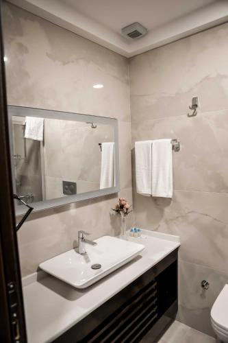 a white bathroom with a sink and a mirror at Dimen Hotel in Bursa
