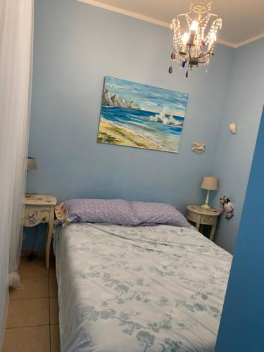 ポルト・レカナーティにあるAppartamentino Celesteのベッドルーム1室(ベッド1台付)が備わります。壁には絵画が飾られています。
