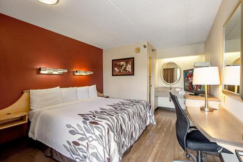 Red Roof Inn St Clairsville - Wheeling West في سانت كليرسفيل: غرفة في الفندق مع سرير ومكتب