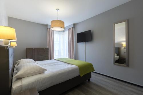Habitación de hotel con cama y espejo en Thon Hotel Residence Parnasse Aparthotel, en Bruselas