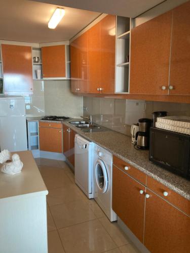 eine Küche mit Holzschränken, einer Waschmaschine und einem Trockner in der Unterkunft "Hasselt" - Amazing Seaview apartment in Ostende