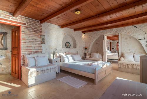 a bedroom with two beds and a brick wall at Blue Caves Villas - exceptional Villas with private pools direct access to the sea in Koríthion