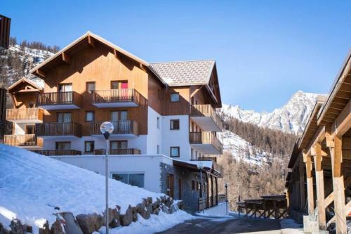 un bâtiment dans les montagnes avec de la neige au sol dans l'établissement Residence Les Gentianes - maeva Home, à Puy-Saint-Vincent