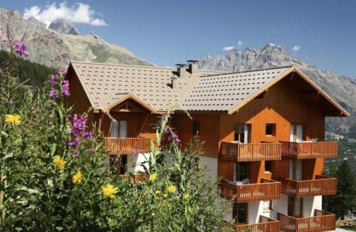 a house with balconies in front of a mountain at Residence Les Gentianes - maeva Home in Puy-Saint-Vincent