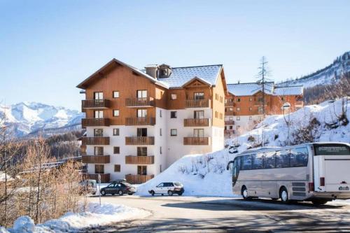 een bus die over een weg rijdt voor een gebouw bij Residence Les Gentianes - maeva Home in Puy-Saint-Vincent