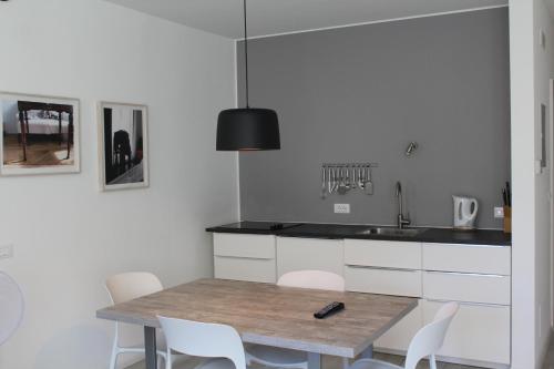 eine Küche mit einem Holztisch und weißen Stühlen in der Unterkunft Apartments Rathaus 008 - Municipio 008 in Bozen