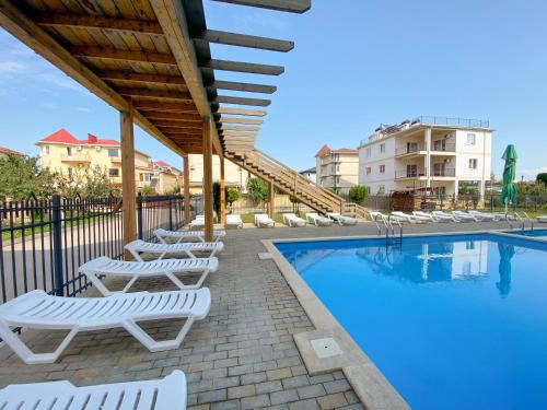 a swimming pool with lounge chairs next to a building at Ambra Resort Hotel All inclusive in Anapa