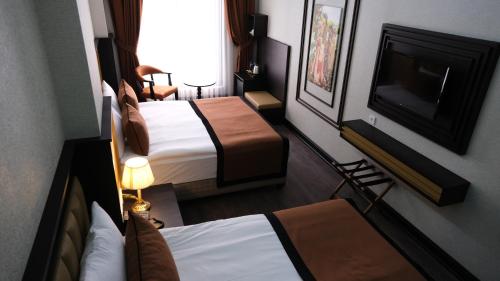 a hotel room with two beds and a flat screen tv at Dimen Hotel in Bursa