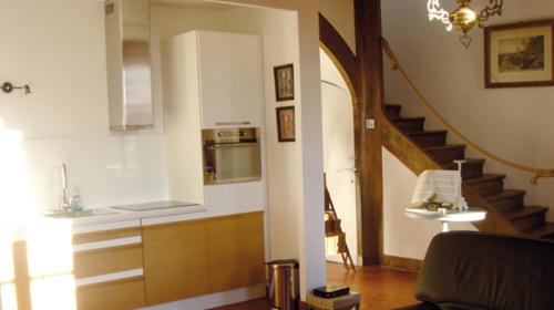 een woonkamer met een keuken en een trap bij Gîte du Domaine du Ru in Aulnoy
