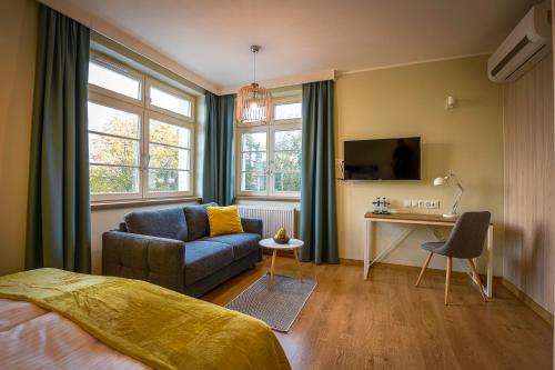 a bedroom with a bed and a couch and a desk at Villa Bałtycka in Gdańsk
