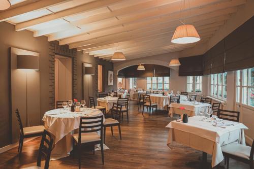 ein Restaurant mit weißen Tischen, Stühlen und Fenstern in der Unterkunft Hotel Serenella in Baveno