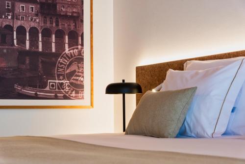 - un lit avec des oreillers blancs et une photo sur le mur dans l'établissement Canadiano Urban Nature Hotel, à Ponta Delgada