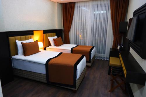 a hotel room with two beds and a flat screen tv at Dimen Hotel in Bursa