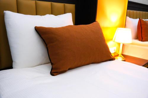 Una cama con una almohada marrón encima. en Dimen Hotel en Bursa
