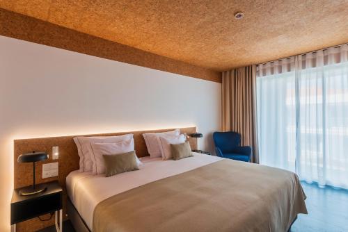 a bedroom with a large bed and a large window at Canadiano Urban Nature Hotel in Ponta Delgada