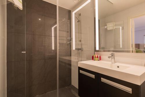 a bathroom with a sink and a glass shower at Thon Residence Florence Aparthotel in Brussels