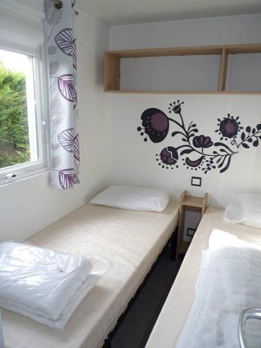 deux lits dans une chambre avec une fenêtre dans l'établissement Mobilhome 6 places Les Charmettes 81, aux Mathes