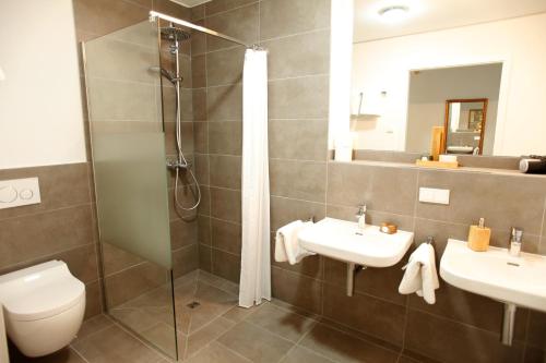 a bathroom with two sinks and a shower at Boardinghotel Westarkaden Suites in Heidelberg