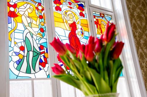 a vase with red flowers in front of a stained glass window at Zolota Pava in Berehove