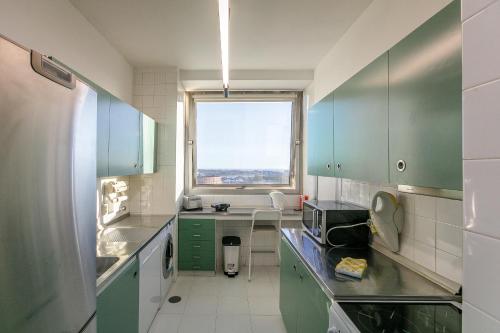 a kitchen with green cabinets and a window at LovelyStay - Spacious 3BR Flat with AC and Balcony in Porto