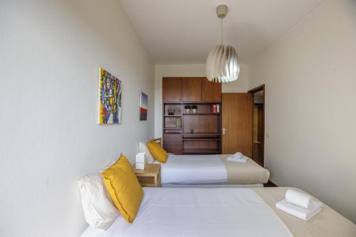 two beds in a small room with yellow pillows at LovelyStay - Spacious 3BR Flat with AC and Balcony in Porto