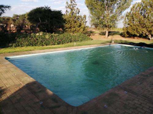 a swimming pool with blue water in a yard at Hippo Farm Apartment in Gobabis