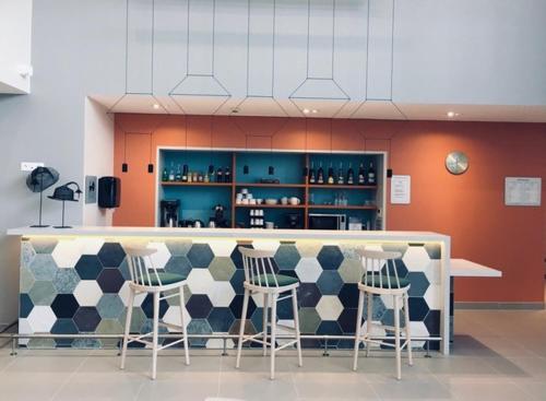 a kitchen with a counter with stools and a bar at Résidence Services DOMITYS La Cantate in Dunkerque
