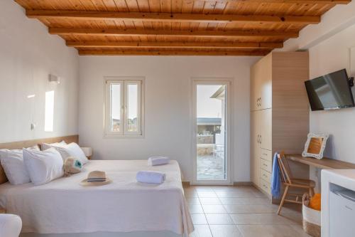 um quarto com uma cama grande e uma televisão em Sea Wind Villas and Suites em Tourlos