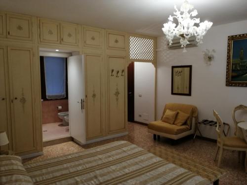 a bedroom with a bed and a chair and a chandelier at Hotel Orion in Venice