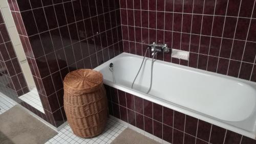 - une salle de bains pourvue d'une baignoire blanche et d'un panier dans l'établissement Ferienhaus am Waldrand, à Ampflwang im Hausruckwald
