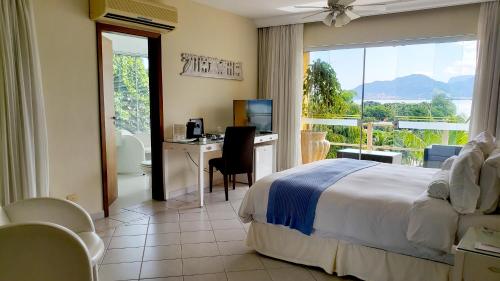 a bedroom with a bed and a desk with a computer at Hotel Itapemar - Ilhabela in Ilhabela